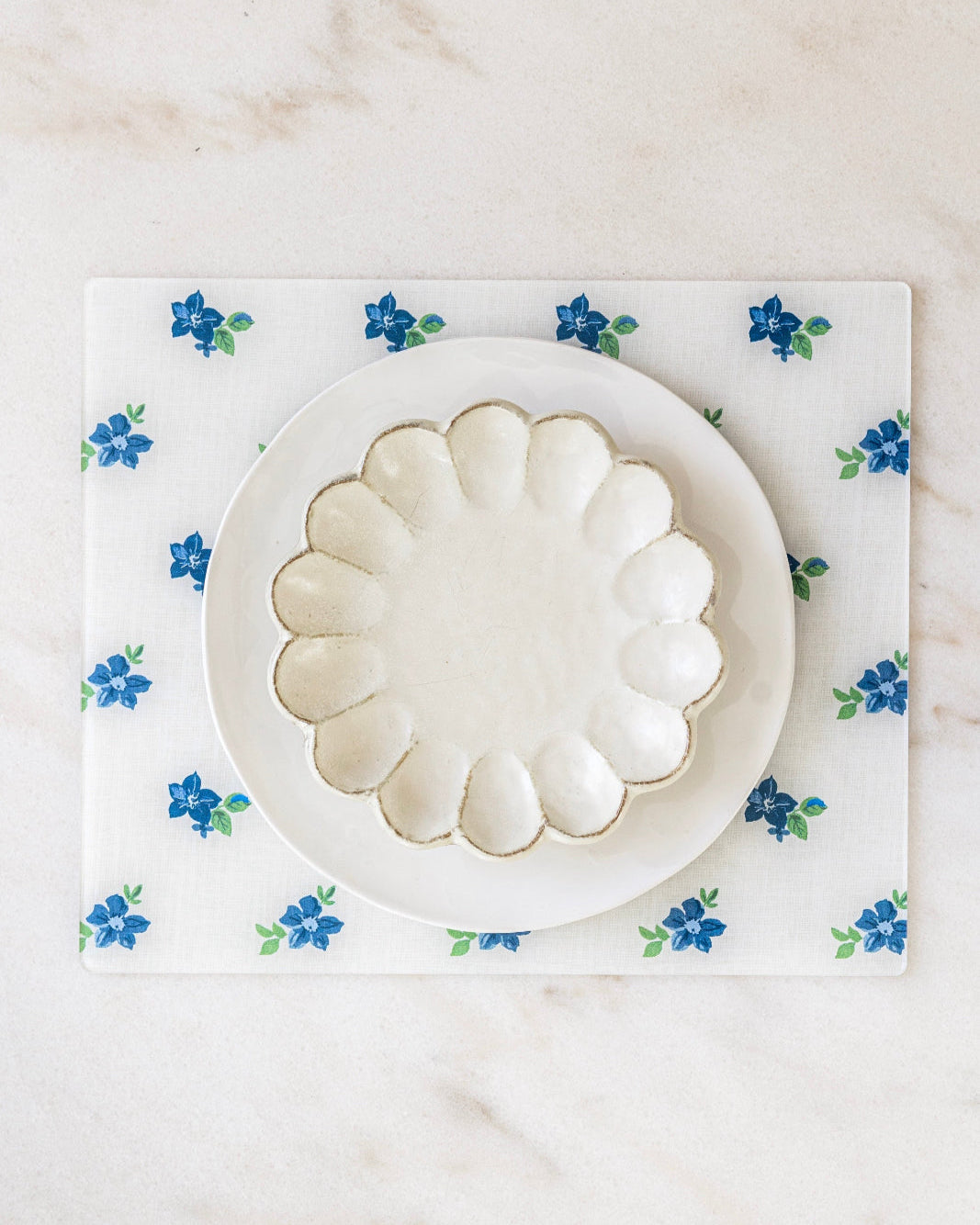 Rectangle floral placemat in blues and whites at marble dining table.