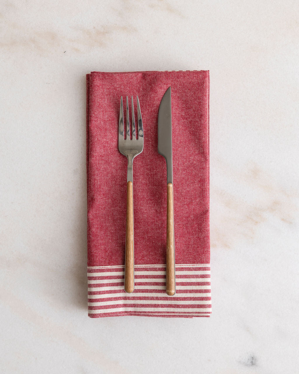 Phineas pink striped napkin with a fork and knife on a marble surface
