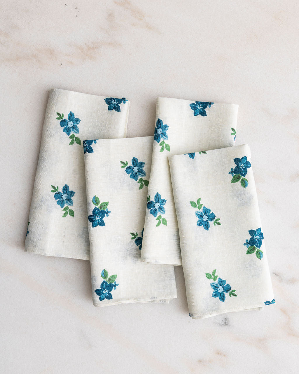 Set of four Anna white and blue floral napkins on a marble table