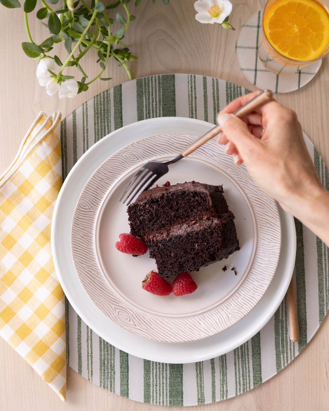 
                  
                    Nathan Turner Interiors and Proper Table Co. green striped round placemat with chocolate cake and yellow gingham napkin.
                  
                