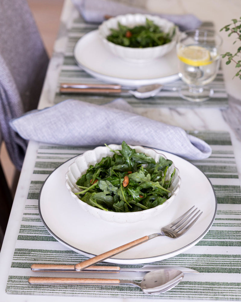 
                  
                    Two bowls of green salad on a table with green striped Proper Table placemats and cutlery.
                  
                