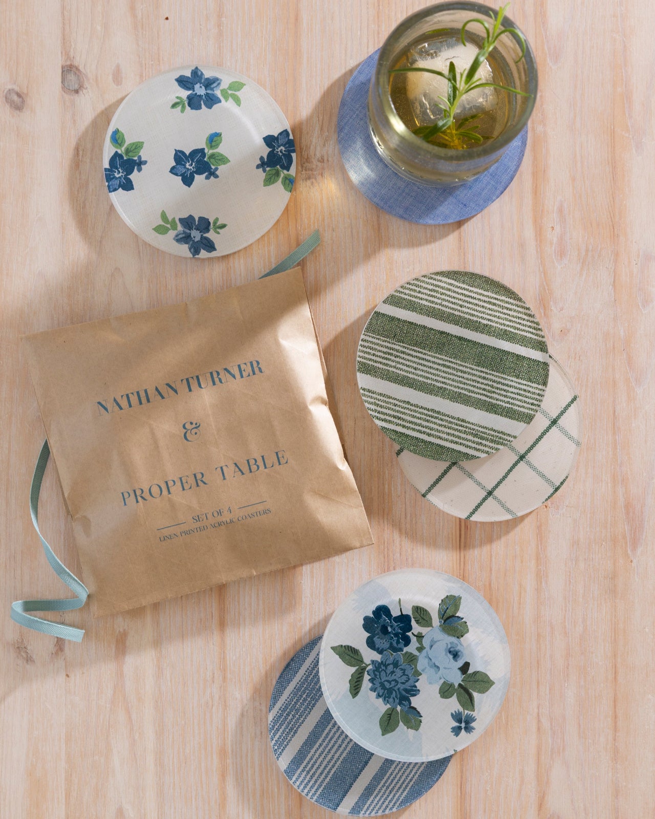 Set of floral and patterned coasters on a wooden surface with a package labeled 'Nathan Turner x Proper Table'.