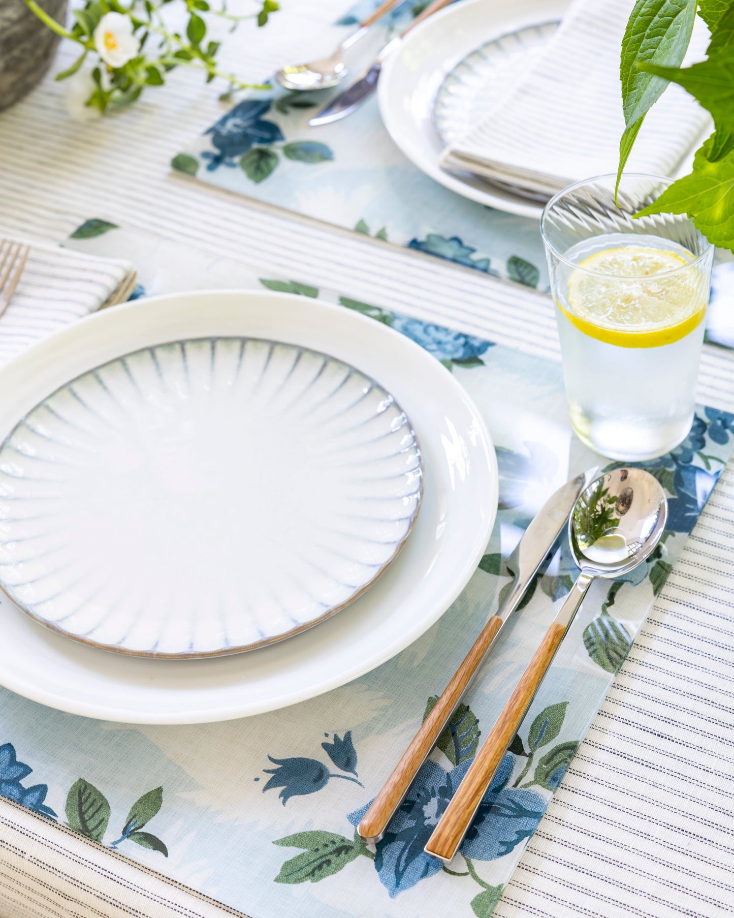 
                  
                    Elegant table setting with Nathan Turner x Proper Table Theodora acrylic placemats and crisp white plates. 
                  
                