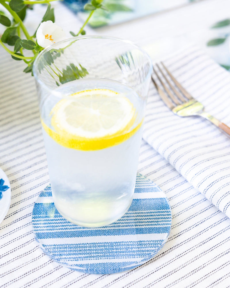 Cool glass of water with a lemon on a blue striped acrylic coaster made by Proper Table.