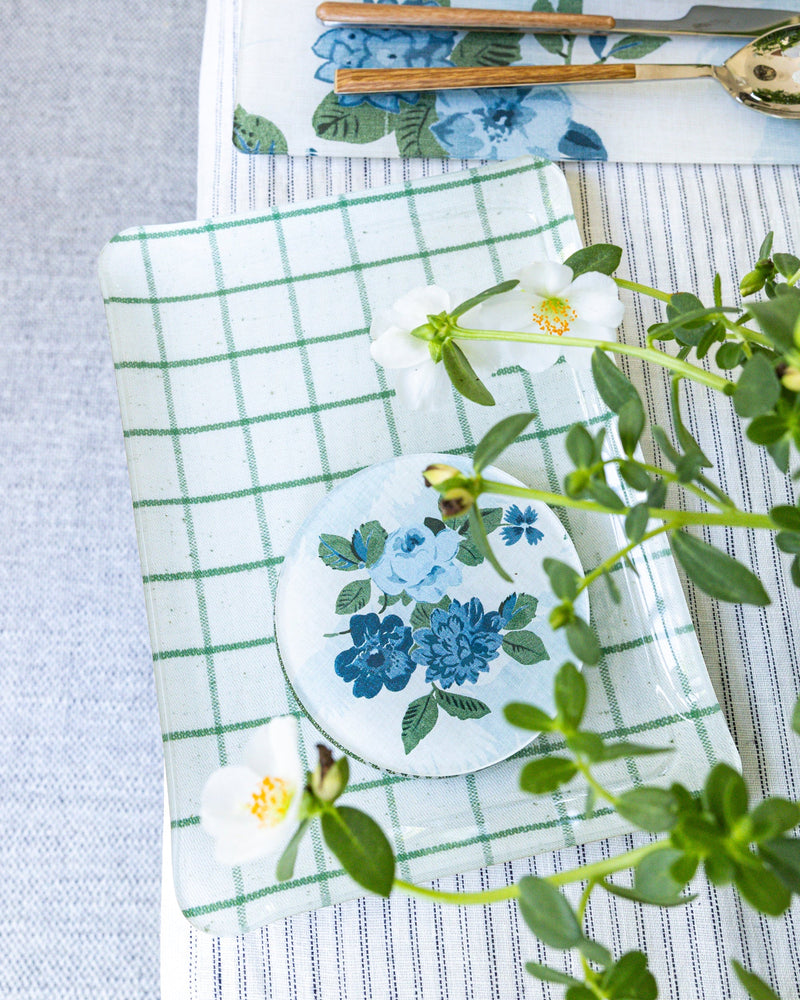 Table setting with Proper Table x Nathan Turner floral coasters and placemats, on a striped tablecloth.