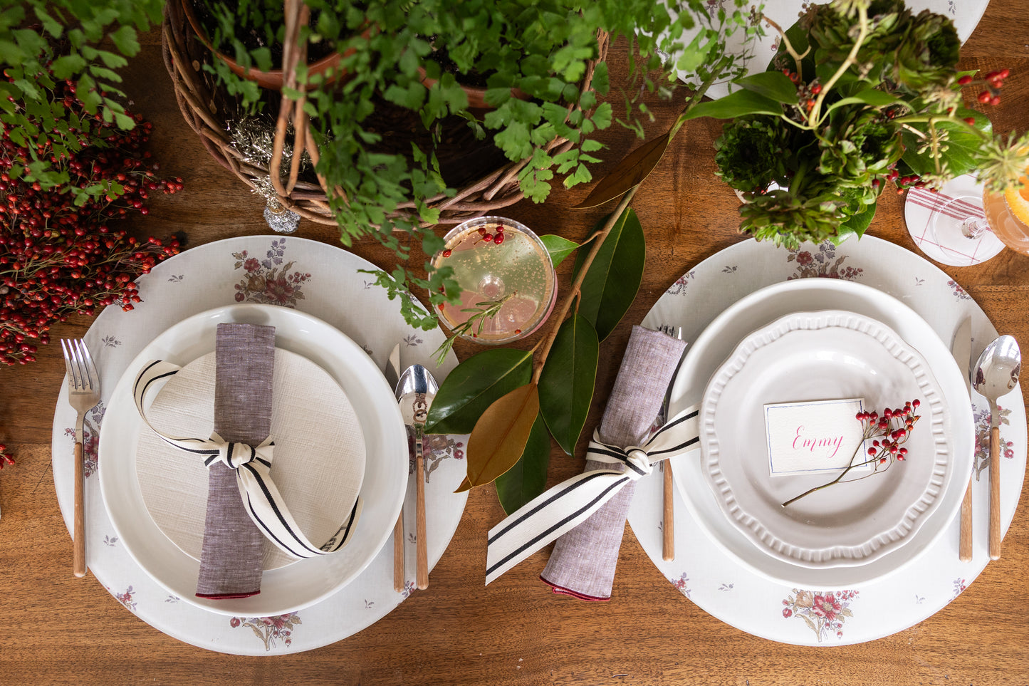 Round acrylic floral placemat from Proper Table x Leah O’Connell Design, styled with layered white plates and a ribbon-tied linen napkin on a wooden table  for holiday.