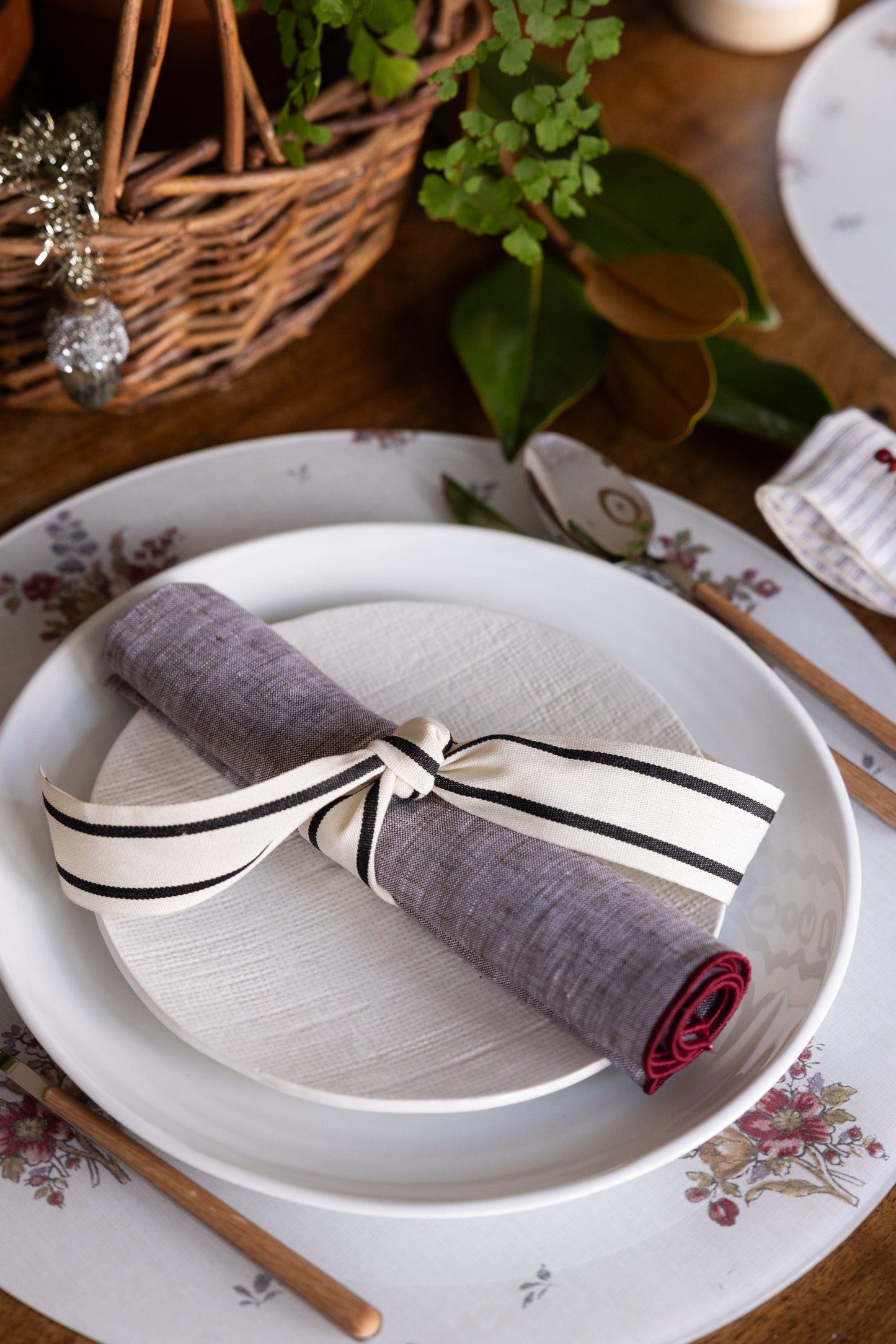 
                  
                    Round floral acrylic placemats from Proper Table x Leah O’Connell, styled in a festive holiday tablescape with magnolia leaves, ribbon-tied napkins, and scalloped plates. Placemats are Gigi fabric.
                  
                