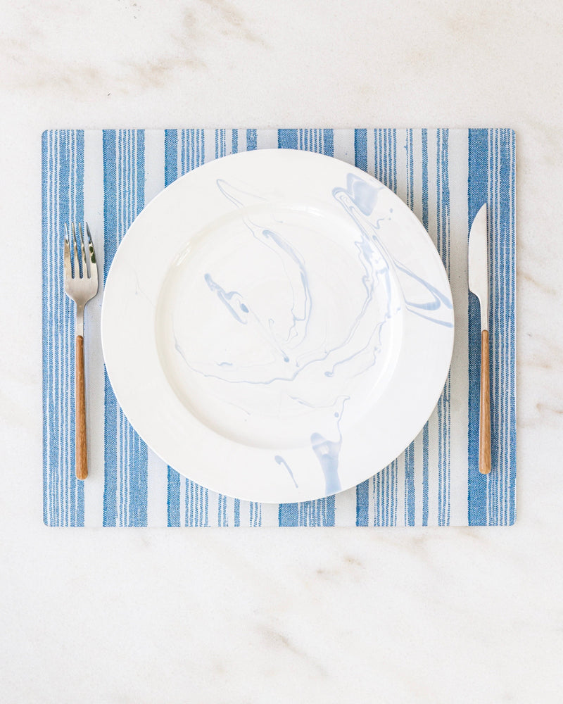 Rectangle placemat in blue striped fabric from a collaboration between Proper Table and Nathan Turner Interiors on marble.